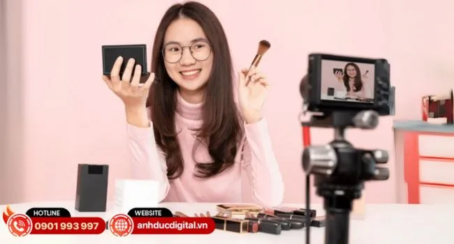 Bàn làm việc với các sản phẩm được sắp xếp gọn gàng để livestream, cùng với máy tính và kịch bản, cho thấy sự chuẩn bị danh sách sản phẩm chi tiết nhằm tối ưu hóa live stream Youtube.